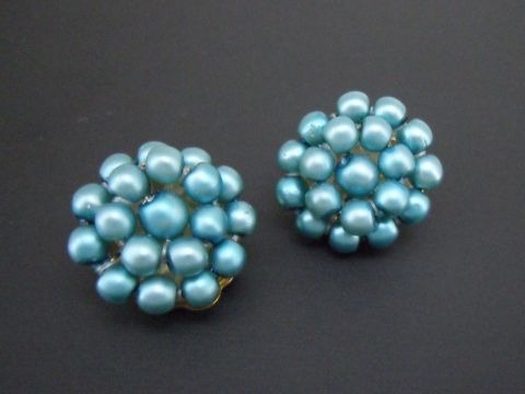 Ohrclip in dunkeltürkis mit perlentraum Effekten aus goldfarbenem Material und seidenmatten synthetischen Zuchtperlen, hergestellt von Juwelier Harnisch.