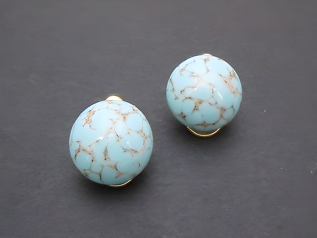 Ohrclip in klassischem Design mit türkisfarbenen, synthetischen Kugeln und goldfarbenem Rahmen, Hersteller Juwelier Harnisch, zeitlos und elegant.