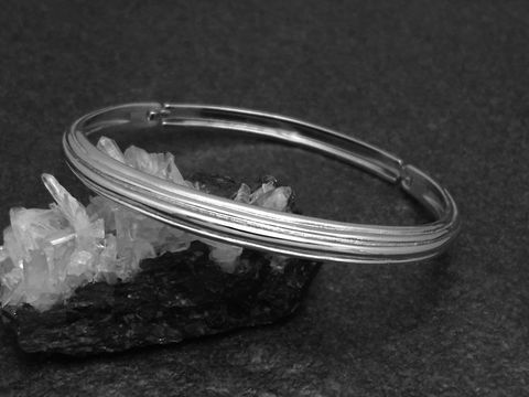 Silber Armreifen weiblich 6 mm rhodiniert 16,5 cm von Juwelier Harnisch, elegant auf schwarzem Hintergrund mit Kristallen drapiert. Ideal für stilvolle Akzente.