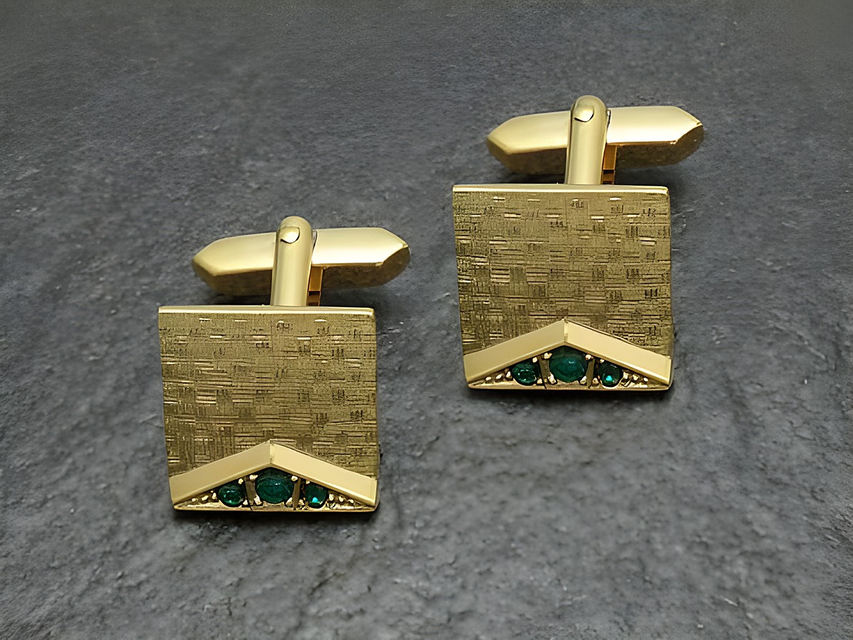 Vergoldete Manschettenknöpfe mit grün funkelndem Strass, Hersteller Juwelier Harnisch, goldfarbenes Design mit geometrischem Muster und eleganter Akzentuierung.