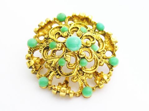 Brosche im Sexy City Look in türkisfarbig rund, mit filigranem goldfarbenem Design und verschiedenen türkisfarbenen Steinen, Hersteller Juwelier Harnisch, Broschen Türkis Look.