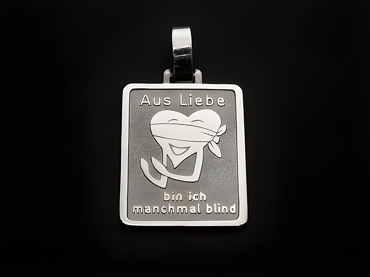 Silber Anhänger mit der Gravur Aus Liebe bin ich manchmal blind, kombiniert mit einem lustigen Herzmotiv, Hersteller Juwelier Harnisch. Ideal für liebevolle Geschenke.