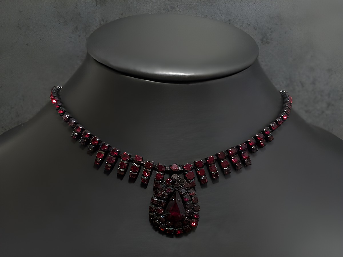 Dunkelrote Strass Kette von Juwelier Harnisch mit einer Fassung in Schwarz, Länge von 45,5 bis 49 cm, geschmückt mit funkelnden Steinen und einem auffälligen Tropfenanhänger.