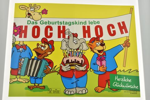 Eine farbenfrohe Geburtstagskarte mit tanzenden Tieren, die ein großes Banner mit Hoch hoch halten. Ein Elefant mit einer Geburtstagstorte und weitere Tiere feiern freudig. Hersteller Juwelier Harnisch.
