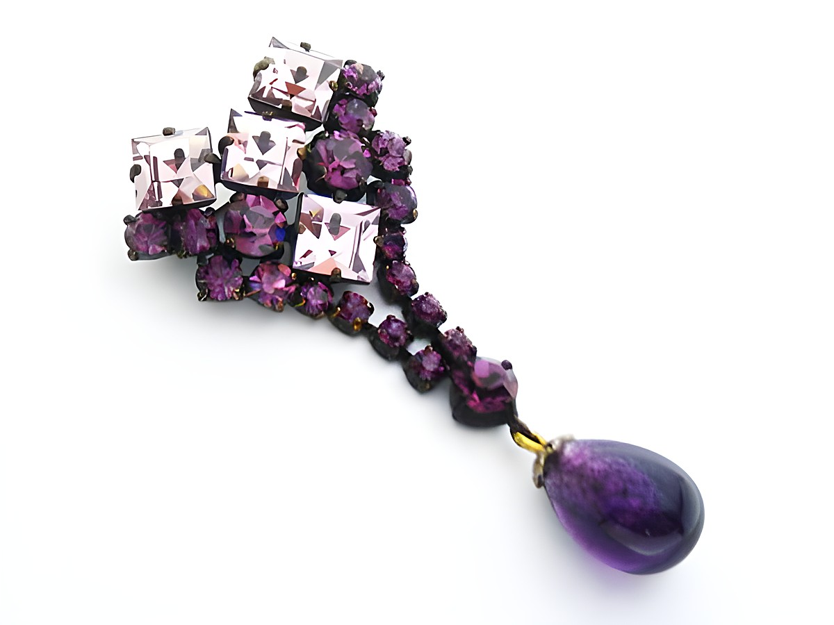 Lila Strass Damen Designer Brosche von Juwelier Harnisch mit elegantem Sexy City Look, funkelt mit verschiedenen lila Steinen und einem tropfenförmigen Anhänger in dunklem Lila.