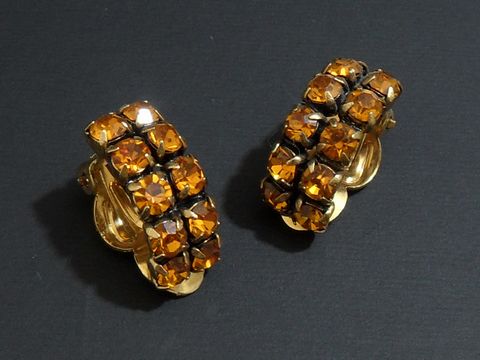 Strass Ohrclips in galantem Design mit orangefarbenen, funkelnden Steinen und goldfarbener Fassung, Hersteller Juwelier Harnisch, ideal für elegante Anlässe.