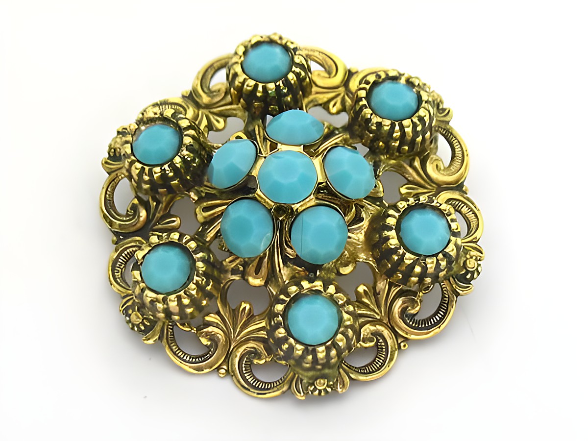 Brosche im Sexy City Look in Türkis, rund mit goldfarbener Verzierung und facettierten Steinen, Hersteller Juwelier Harnisch, idealer Schmuck für stilvolle Akzente.