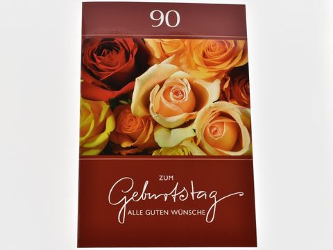 Eine Geburtstagskarte mit der Aufschrift zum Geburtstag alle guten Wünsche und der Zahl 90, umgeben von bunten Rosenblüten in verschiedenen Farben. Hersteller: Juwelier Harnisch, Geburtstagskarten.
