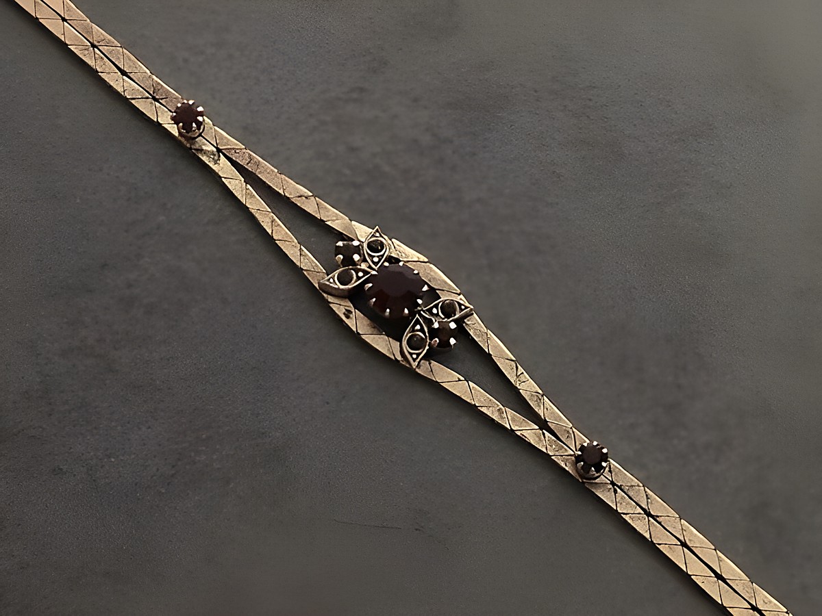 Strass Armband in prunkvollem Design, mit granatrot-farbigen Elementen, goldfarben, verstellbar von 19 bis 21 cm, hergestellt von Juwelier Harnisch, ideal für festliche Anlässe.