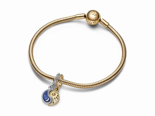 Bicolor Sonne und Mond Charm-Anhänger von Pandora in Sterling Silber und Gelbgold Vergoldung, auf einem goldfarbenen Armband montiert, strahlt Eleganz und Symbolik aus.
