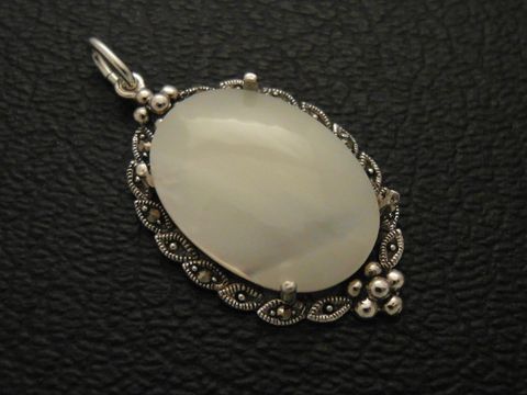 Cabochon Perlmutt in weiß, eingefasst in einem eleganten silbernen Medaillon Anhänger von Juwelier Harnisch, kunstvoll gestaltet mit feinen Details und glänzenden Akzenten.