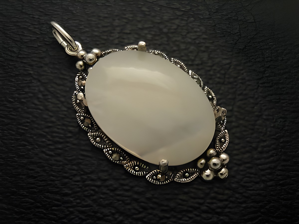 Cabochon Perlmutt in weiß, eingefasst in einem eleganten silbernen Medaillon Anhänger von Juwelier Harnisch, kunstvoll gestaltet mit feinen Details und glänzenden Akzenten.