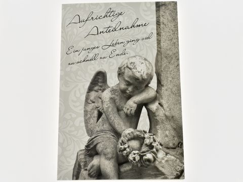Trauerkarte mit einem Engel, der nachdenklich mit einer Blumenkranz sitzt. Die Schriftzüge "Aufrichtige Anteilnahme" und "Ein junges Leben ging viel zu schnell zu Ende" sind auf dem Hintergrund sichtbar.