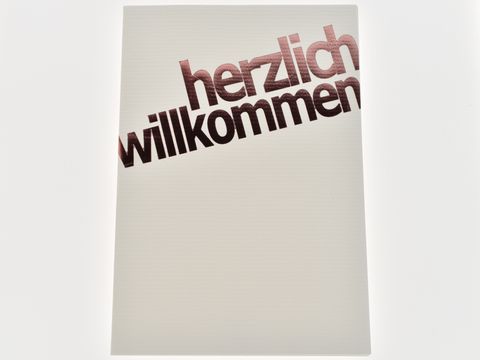 Glückwunschkarte in dezentem Design mit kupferfarbener Schrift. Auf der Karte steht herzlich willkommen. Hergestellt von Juwelier Harnisch, Glückwunschkarten.
