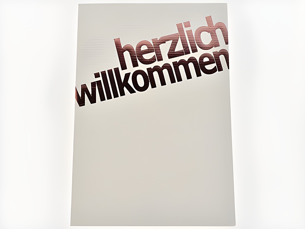 Glückwunschkarte in dezentem Design mit kupferfarbener Schrift. Auf der Karte steht herzlich willkommen. Hergestellt von Juwelier Harnisch, Glückwunschkarten.
