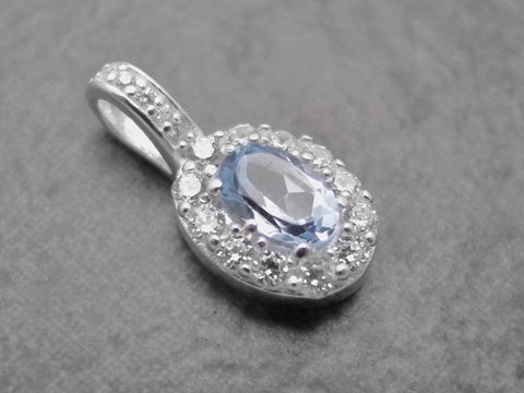 Ovaler Anhänger aus Sterling Silber mit blauem Blautopas im Mittelpunkt, umgeben von weißen Zirkonia, elegant und edel, Hersteller Juwelier Harnisch, ideal für Schmuckliebhaber.