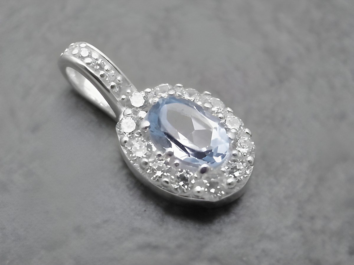 Ovaler Anhänger aus Sterling Silber mit blauem Blautopas im Mittelpunkt, umgeben von weißen Zirkonia, elegant und edel, Hersteller Juwelier Harnisch, ideal für Schmuckliebhaber.
