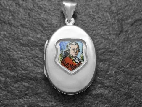 Silbermedaillon mit einer Darstellung von Wolfgang Amadeus Mozart im roten Outfit, umgeben von dekorativen Elementen. Hergestellt von Juwelier Harnisch, Europa Medaillons.