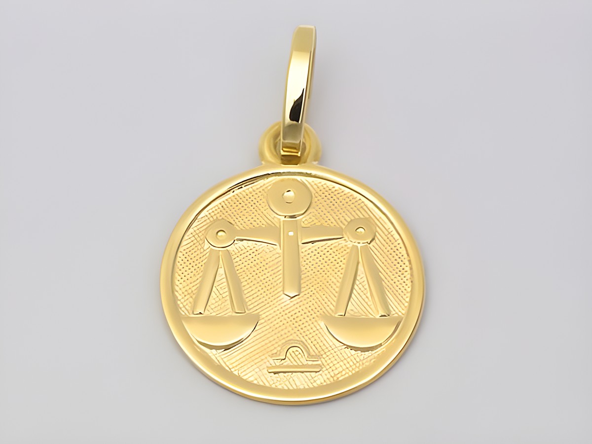 Eine polierte goldene Medaille mit dem Motiv der Waage, Symbol des Sternzeichens Waage, Durchmesser 14 mm, Hersteller Juwelier Harnisch.