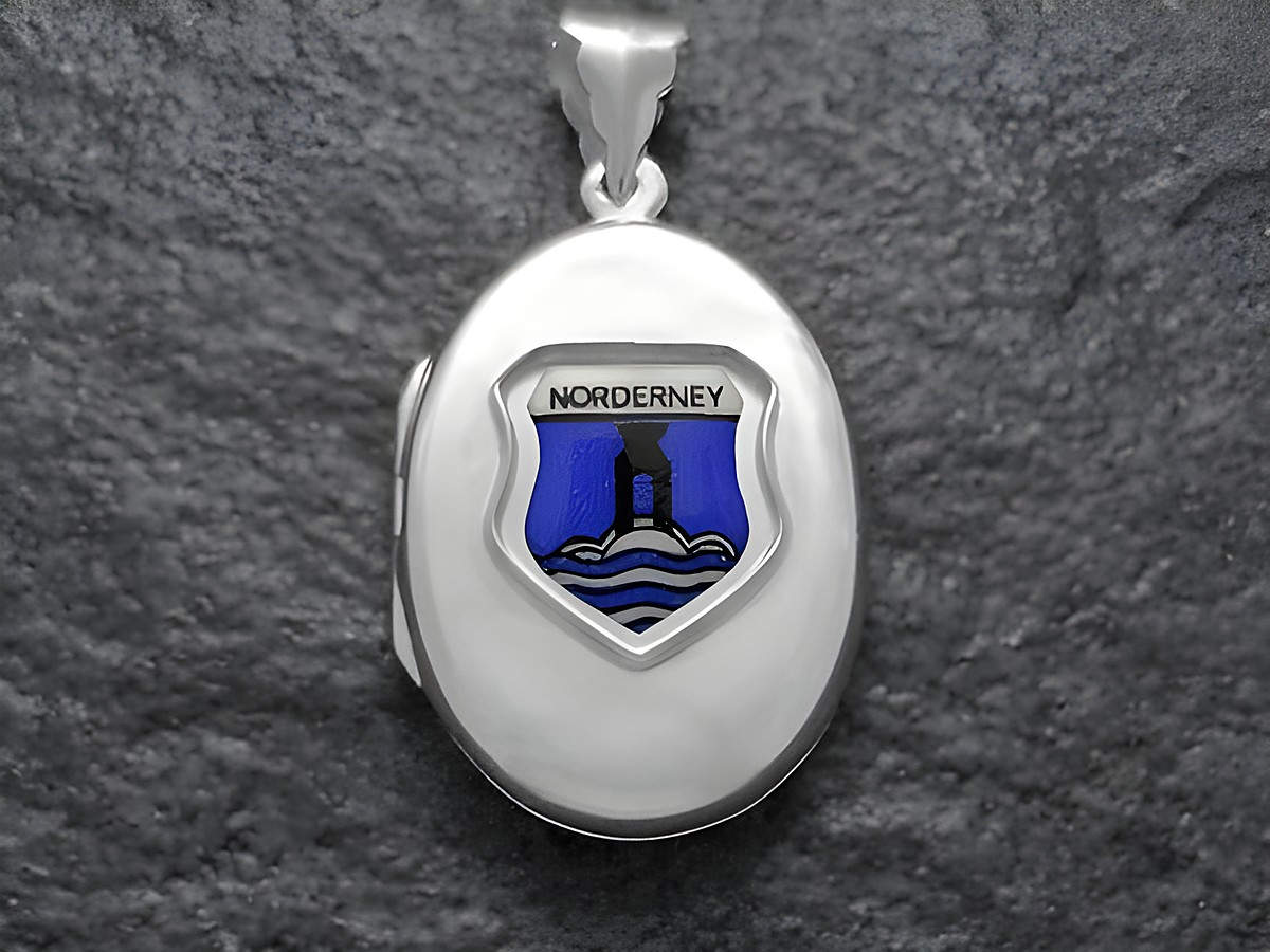 Ein silbernes Medaillon mit dem Wappen von Norderney. Das Wappen zeigt ein blaues Schild mit einem Leuchtturm und Wellen, hergestellt von Juwelier Harnisch.