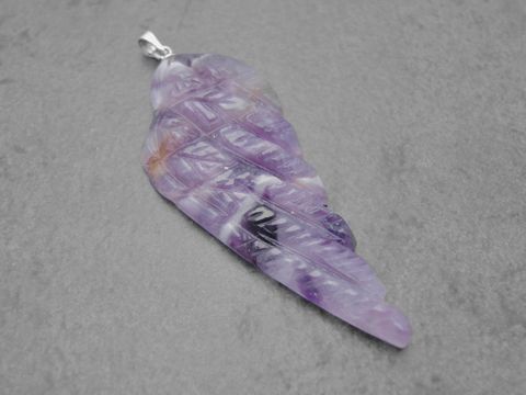 Ein Anhänger in Form eines Engels mit Flügeln aus lila-weiß-braunem Amethyst, 5 cm groß, mit einer Silberöse zum Anhängen, hergestellt von Juwelier Harnisch.