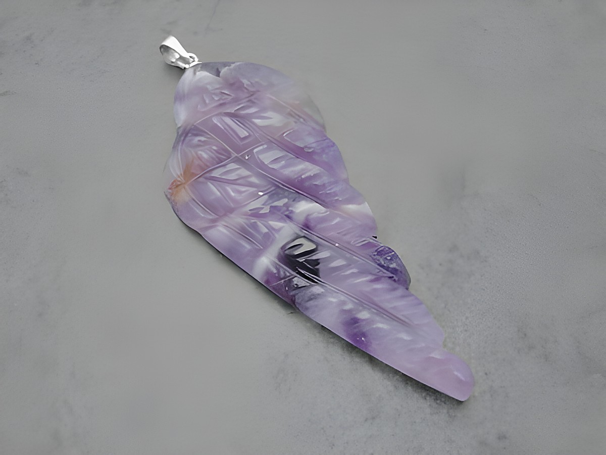 Ein Anhänger in Form eines Engels mit Flügeln aus lila-weiß-braunem Amethyst, 5 cm groß, mit einer Silberöse zum Anhängen, hergestellt von Juwelier Harnisch.