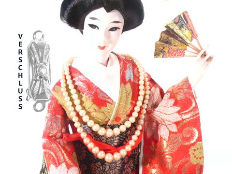 Zwei Reihen Zuchtperlen in einer eleganten Perlenkette mit silbernem Verschluss, hergestellt von Juwelier Harnisch, präsentiert auf einer dekorativen Puppe in traditioneller Bekleidung.