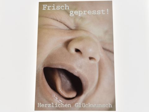 Eine Glückwunschkarte mit einem lächelnden Babygesicht und dem Text Frisch gepresst Herzlichen Glückwunsch. Hersteller ist Juwelier Harnisch.