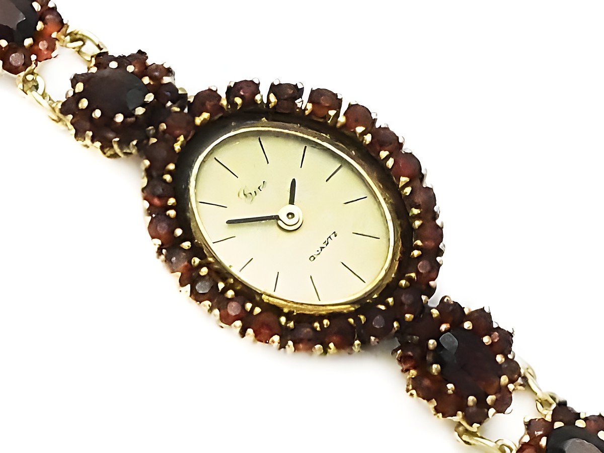 Granat Schmuck Uhr 18 cm mit Blüte aus Gold und Granatschmuck, Hersteller Juwelier Harnisch, verziert mit Stein und Perle, elegantes Design mit ovalem Zifferblatt.