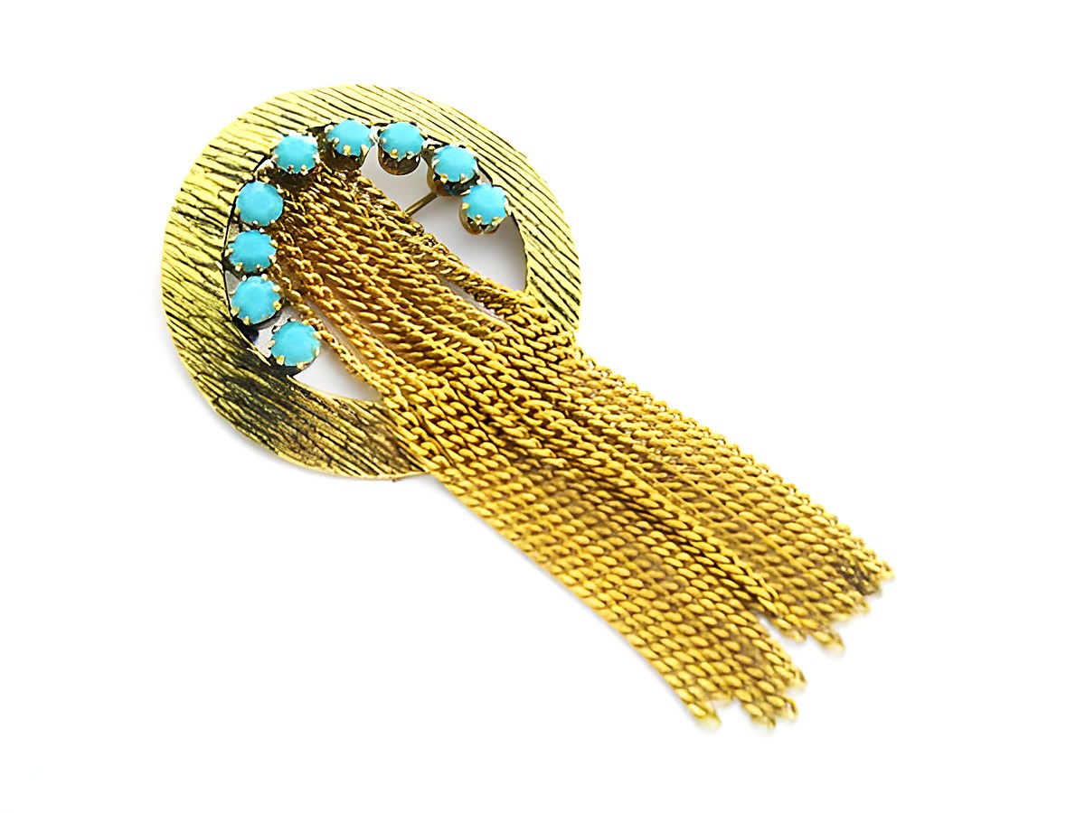 Runde Brosche mit gefassten türkis look Steinen im Strass-Stil. Hersteller Juwelier Harnisch. Die Brosche hat eine goldene Grundstruktur und gestufte Kettenelemente.