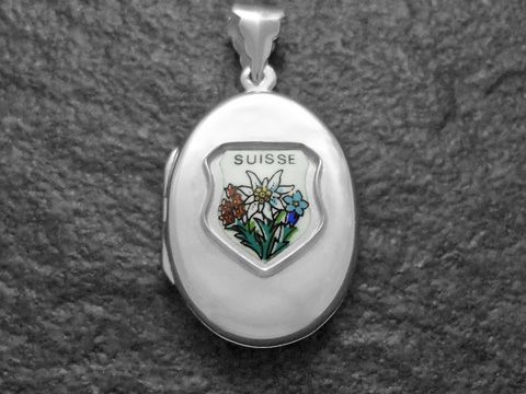 Edelweiß, blauer Enzian und Kohlröschen sind in einem silbernen Medaillon mit dem Schriftzug Suisse dargestellt, hergestellt von Juwelier Harnisch aus Europa.