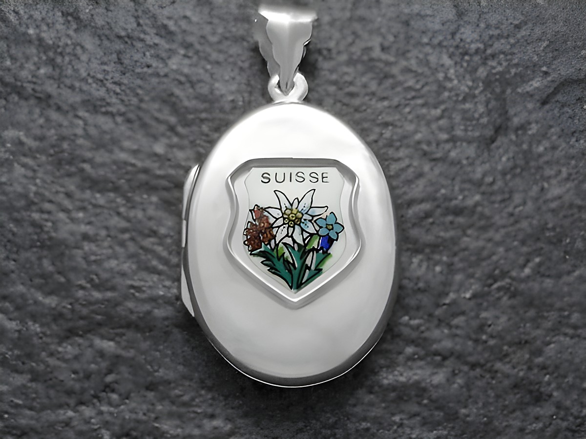 Edelweiß, blauer Enzian und Kohlröschen sind in einem silbernen Medaillon mit dem Schriftzug Suisse dargestellt, hergestellt von Juwelier Harnisch aus Europa.