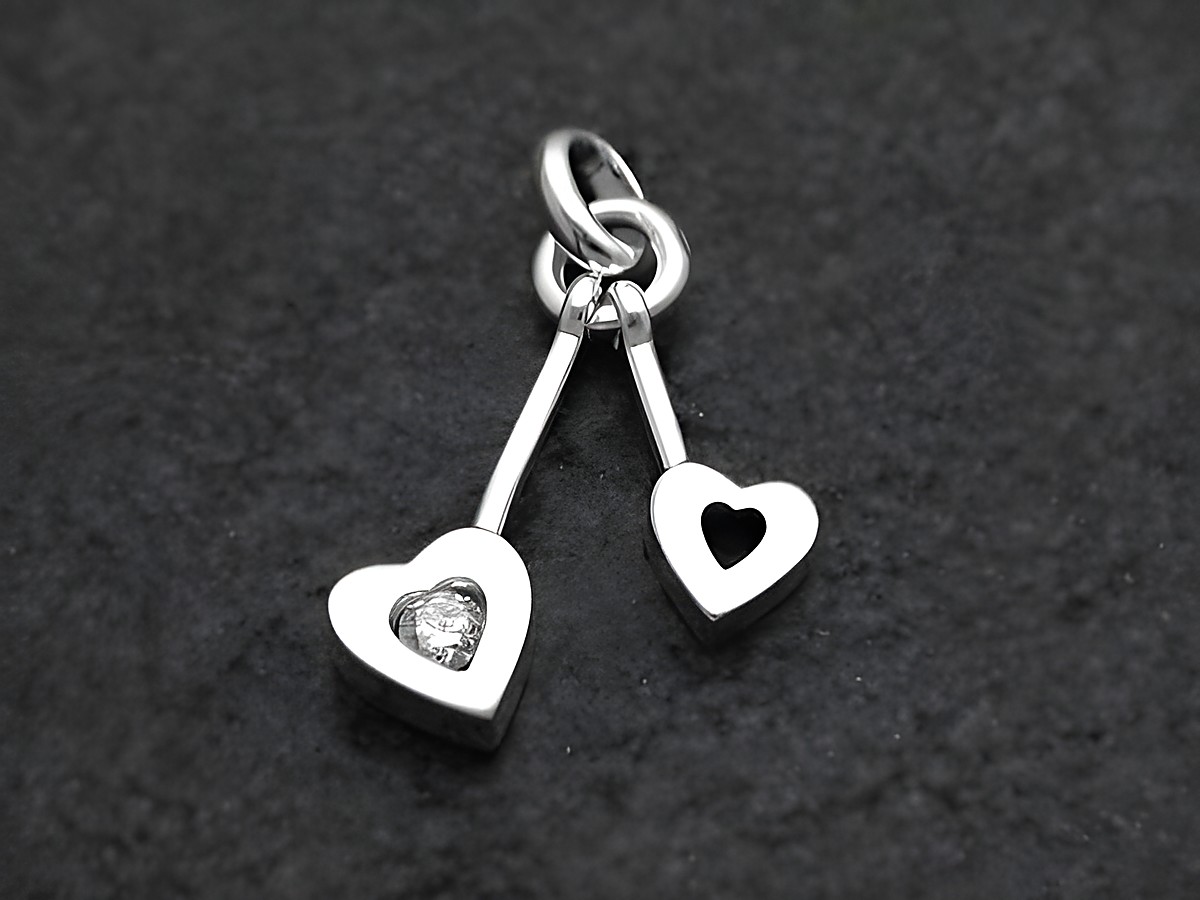 Zwei hängende Herz-Anhänger aus Sterlingsilber 925, einer besetzt mit Zirkonia, der andere mit einem Ausschnitt in Herzform, hergestellt von Juwelier Harnisch.