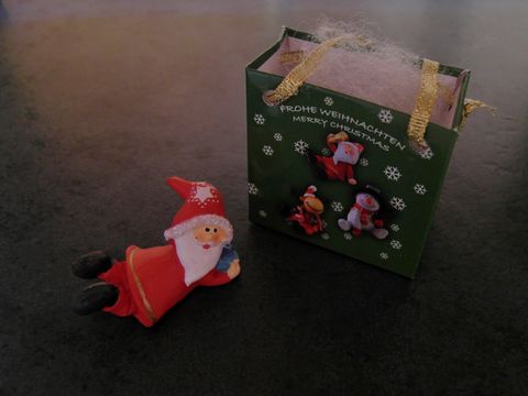 Weihnachtsmann mit Geschenktasche liegend mit Geschenk, Hersteller: Juwelier Harnisch, Weihnachten.