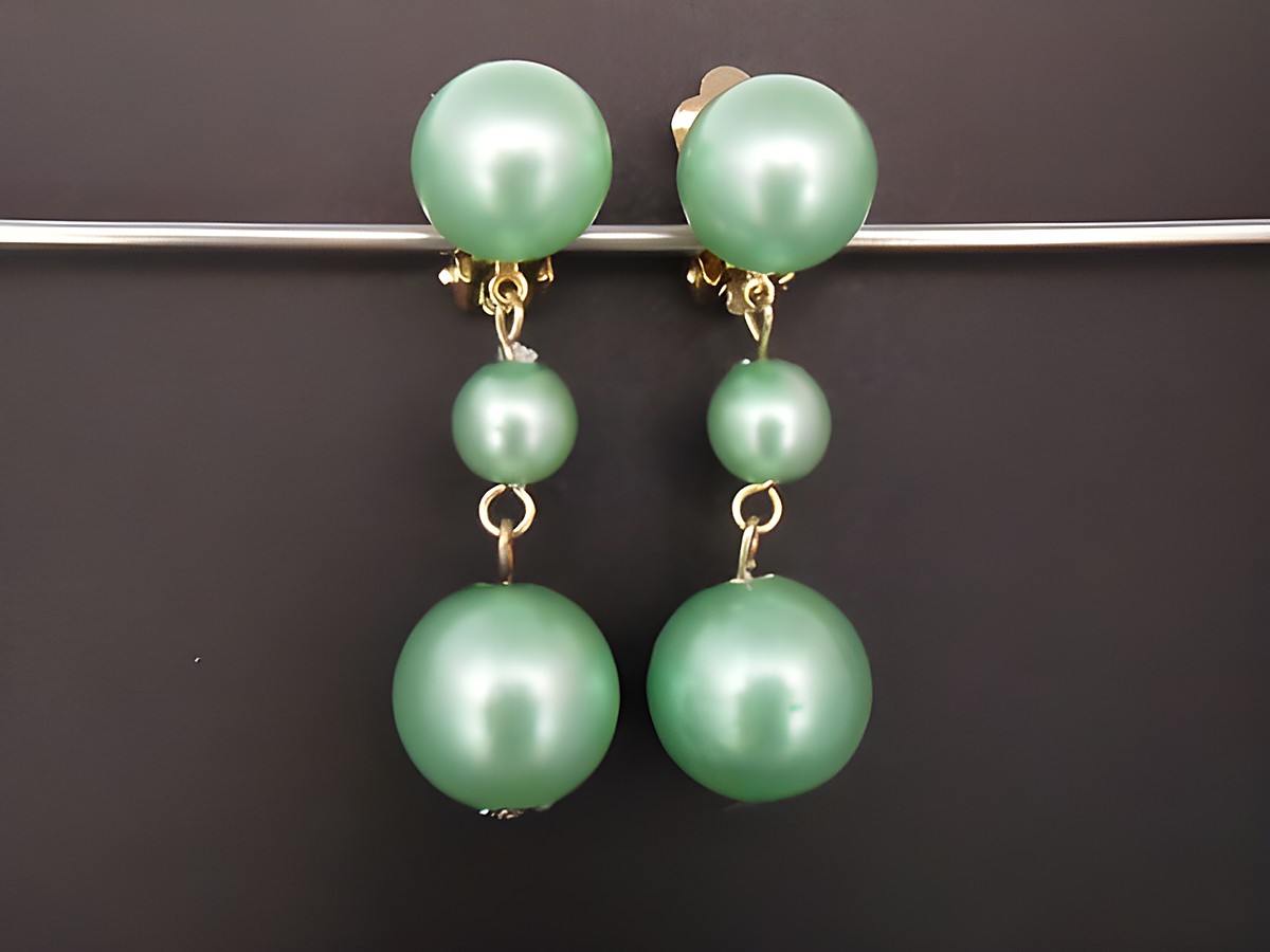 Ohrclip in zeitlosem Design mit türkisfarbenen Kunstharzperlen und goldfarbenen Elementen, hergestellt von Juwelier Harnisch. Ideal für elegante Anlässe.