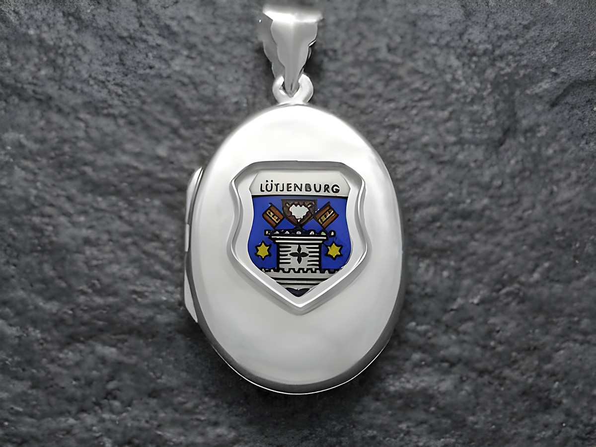 Das Bild zeigt ein silbernes Medaillon mit dem Stadtwappen von Lütjenburg in Schleswig-Holstein. Das Wappen ist farbig mit einer stilisierten Darstellung und befindet sich auf der Vorderseite des Medaillons.