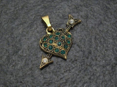Grüner Strass Anhänger im Sexy City Look in Herzform mit Pfeilen, gefertigt von Juwelier Harnisch. Funktionsreicher und eleganter Schmuck, ideal für modische Akzente.