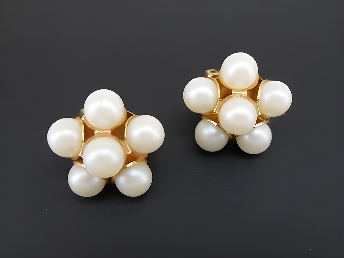Ohrclip in weiß blumigem Design mit goldfarbener Fassung und synthetischen Zuchtperlen, hergestellt von Juwelier Harnisch. Ideal für elegante Anlässe.