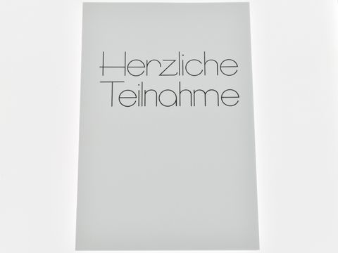 Eine weiße Trauerkarte mit der Schrift "Herzliche Teilnahme" in eleganter, schwarzer Schriftart. Hersteller ist Juwelier Harnisch. Die Karte ist schlicht und würde für Beileidsbekundungen verwendet.