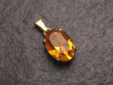 Gelber Strass Anhänger in ovaler Form mit goldfarbener Fassung, ideal für einen sexy City Look, hergestellt von Juwelier Harnisch, perfekt als Schmuckstück für verschiedene Anlässe.
