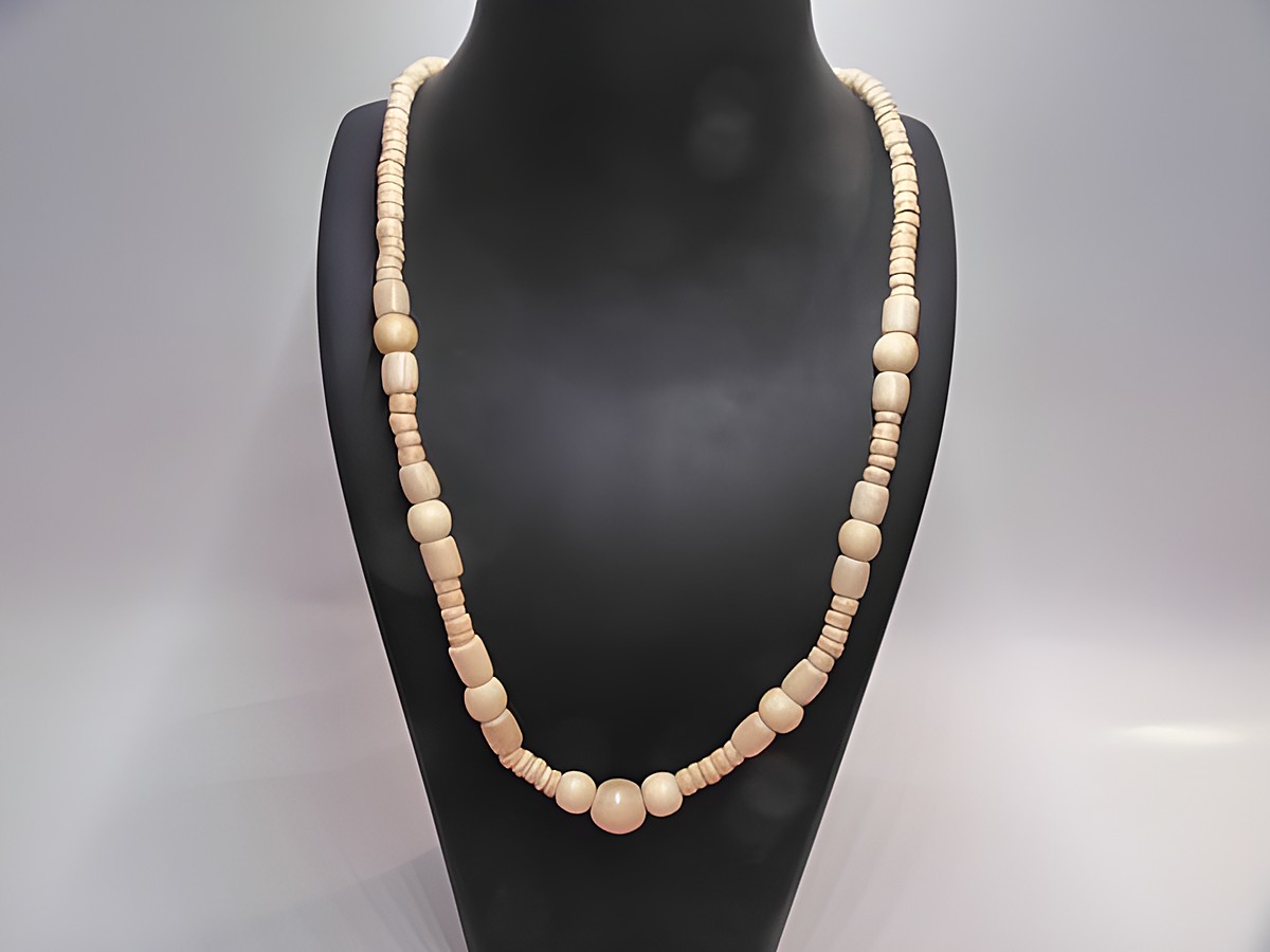 Holzkette Multiform in naturbraun mit einem Durchmesser von 29 mm und einer Länge von 60 cm, hergestellt von Juwelier Harnisch, präsentiert sich elegant auf einem schwarzen Präsentationsständer.