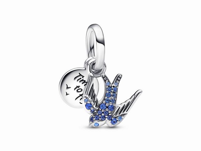 Silberner Pandora Charm Anhänger in Form einer Schwalbe, verziert mit blauen Kristallen, inklusive einer kleinen runden Plakette mit Gravur. Ideal für persönliche Armbänder.