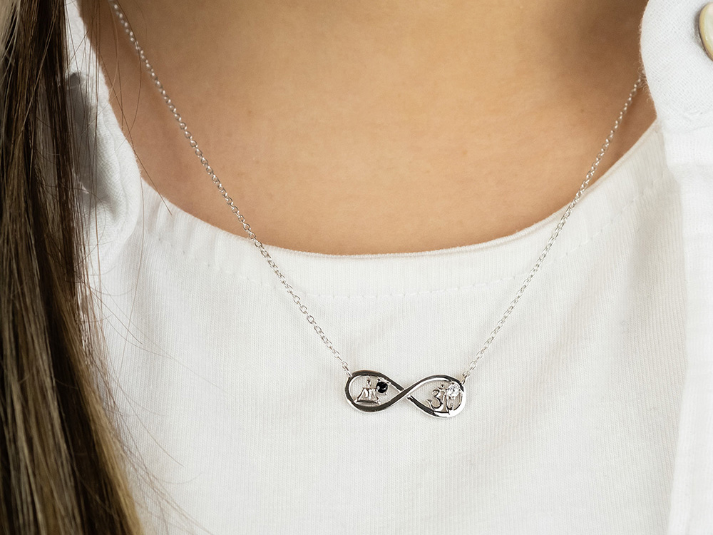 Silberne Engelsrufer Kette mit Yin Yang Symbol und Zirkonia im Infinity Design, getragen von einer Person mit heller Kleidung, Länge 40 + 4 cm. Neuheit des Herstellers Engelsrufer.