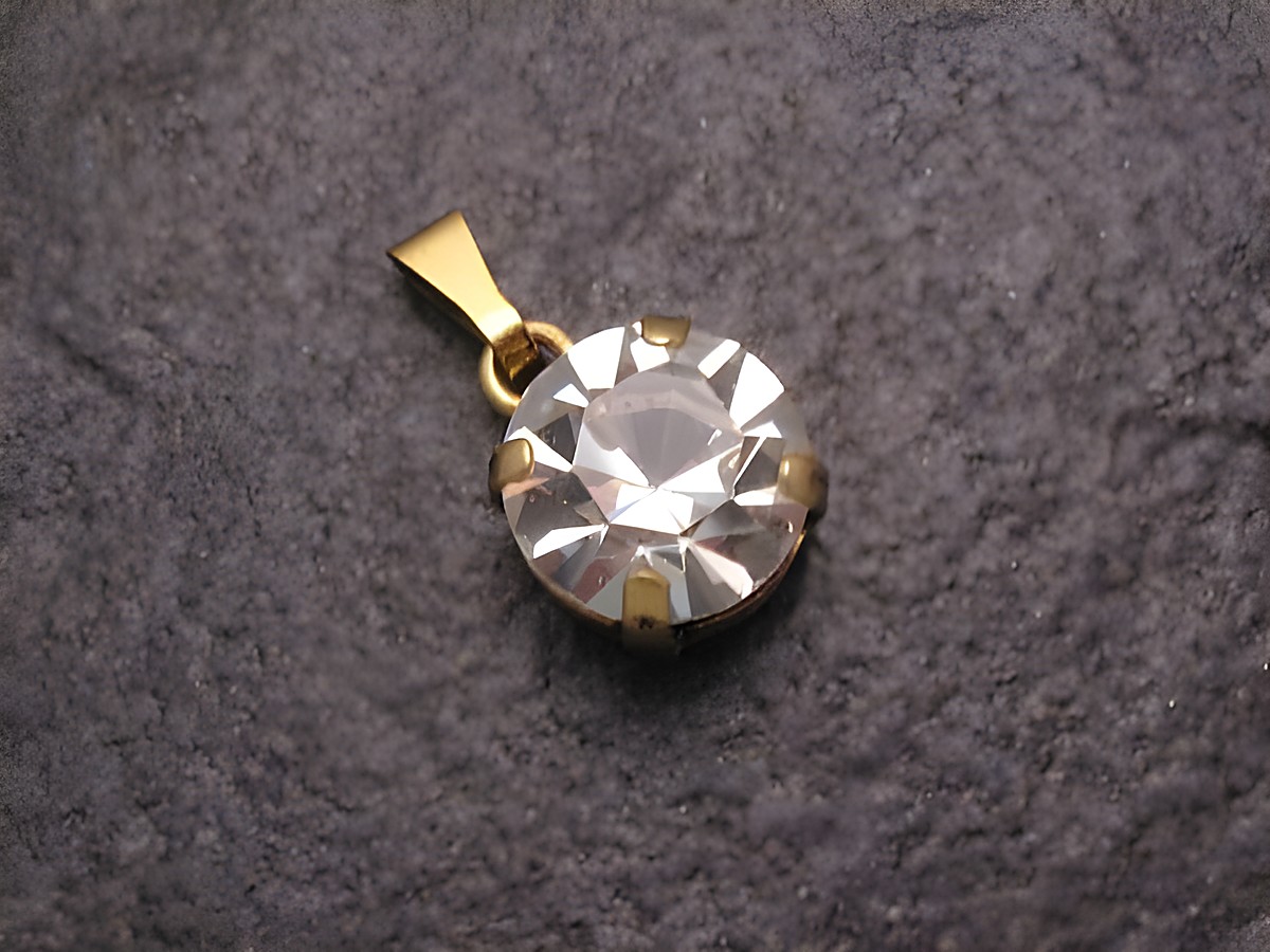 Weißer Strass Anhänger Sexy City Look rund, Hersteller Juwelier Harnisch, mit goldfarbener Öse, funkelt an einer dunklen Oberfläche und eignet sich perfekt für jeden Anlass.