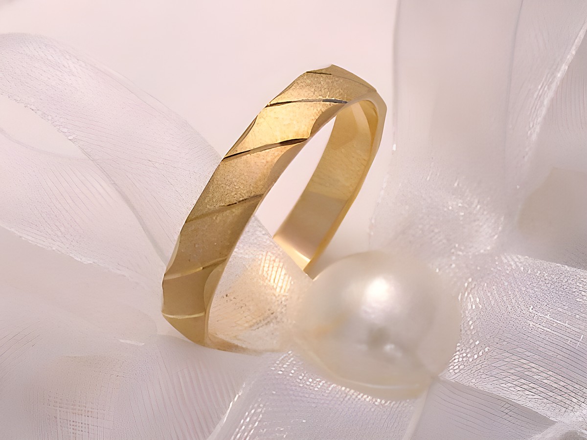 Trauring Ehering SANFT in Gold 585, Größe 54/17,2, Hersteller Juwelier Harnisch, zeigt eine elegante, matte Oberfläche mit dezentem Muster, auf einem weichen Tuch und einer Perle drapiert.