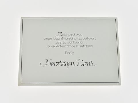 Es ist eine Dankeskarte zu sehen, schlicht in weiß mit schwarzer und silberner Schrift, auf der danken für die Anteilnahme anlässlich eines Verlustes ausgedrückt wird.