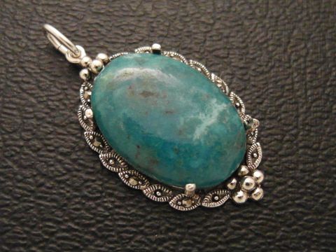 Cabochon in Türkis mit viel Struktur, eingefasst in einem eleganten Silber Medaillon Anhänger, Hersteller Juwelier Harnisch, betont die natürliche Schönheit des Cabochonsteins.