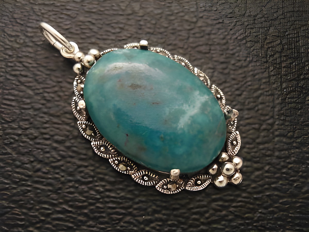 Cabochon in Türkis mit viel Struktur, eingefasst in einem eleganten Silber Medaillon Anhänger, Hersteller Juwelier Harnisch, betont die natürliche Schönheit des Cabochonsteins.