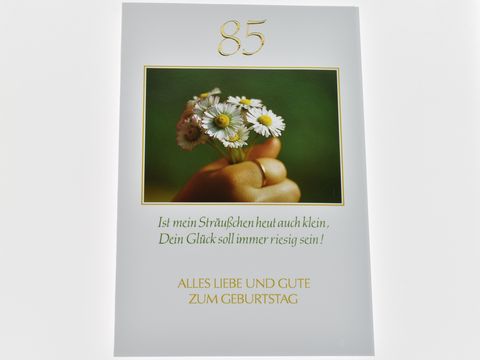 Geburtstagskarte mit der Zahl 85, dekoriert mit einem kleinen Blumenstrauß aus Gänseblümchen, begleitet von der Aufschrift "Alles Liebe und Gute zum Geburtstag" und einem herzlichen Spruch.