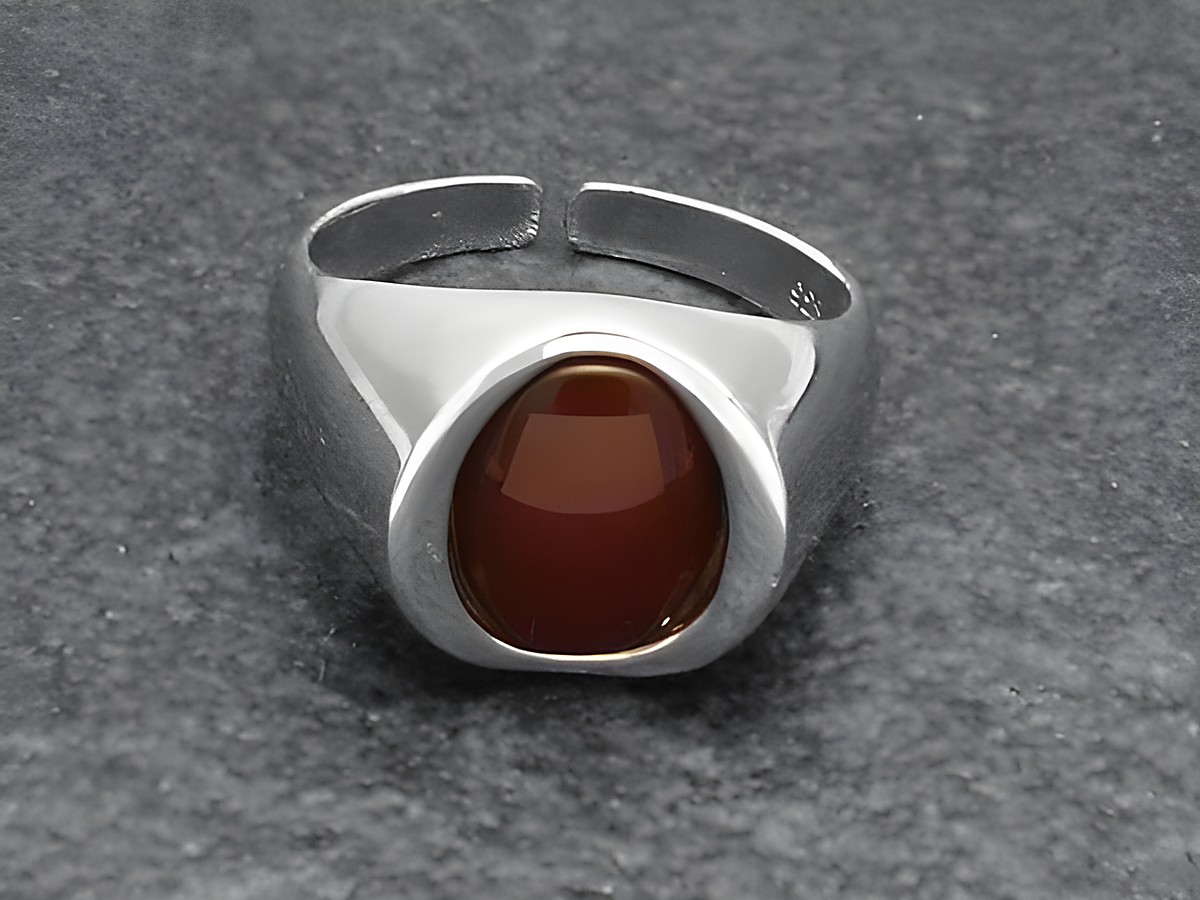 Silberring aus rhodiniertem Material mit einem ovale Karneolstein in der Mitte, modern und verstellbar, elegant und ansprechend, Hersteller Juwelier Harnisch.